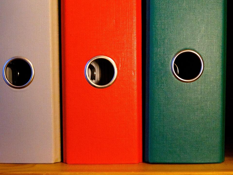Three binders standing in order on a shelf